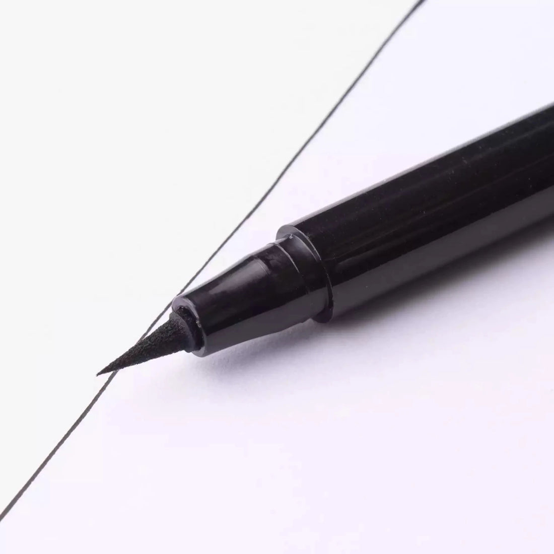 Imagem fechada na ponta da caneta delineadora Pam Beauty Coragem criando um traço preto preciso, ideal para maquiagem dos olhos com alta definição.